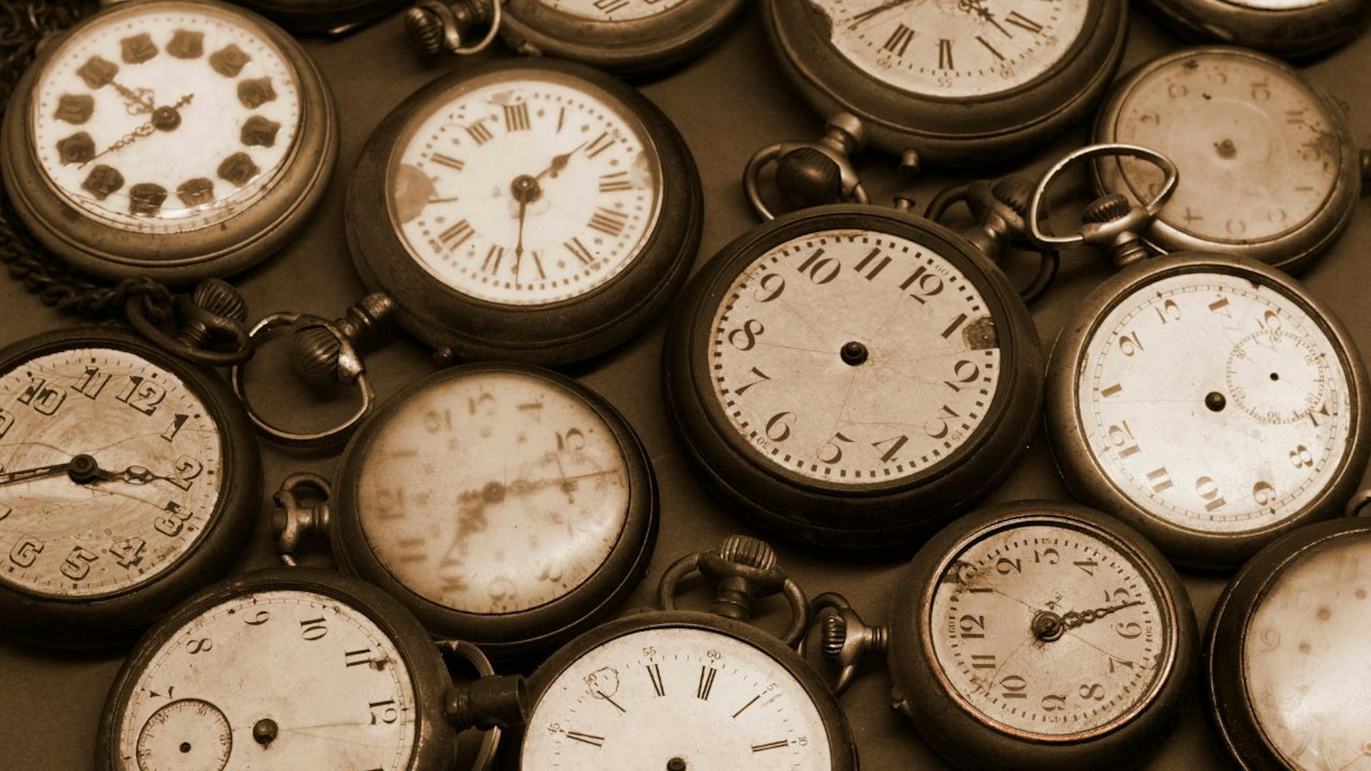 Group of old-fashioned clocks with Roman numerals lying on backs.