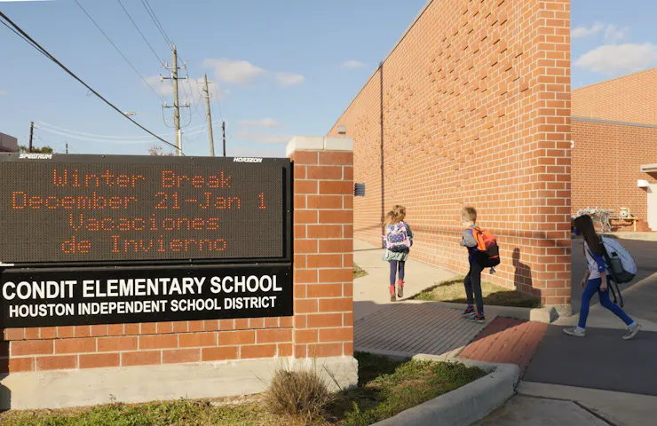 Children are seen walking along a brick wall, past a sign that says 'Condit Elementary School.'