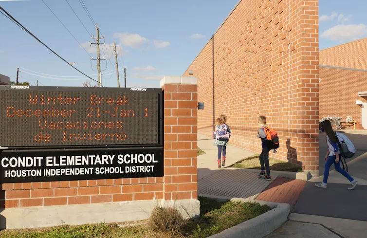 Children are seen walking along a brick wall, past a sign that says 'Condit Elementary School.'