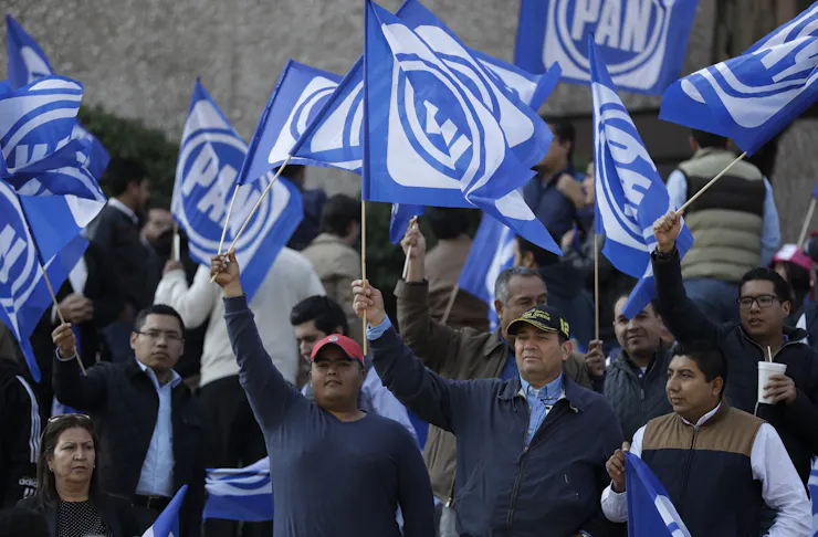 Supporters of the National Action Party (PAN) wave blue and white flags at a rally for their candidate, Ricardo Anaya, in February 2018.