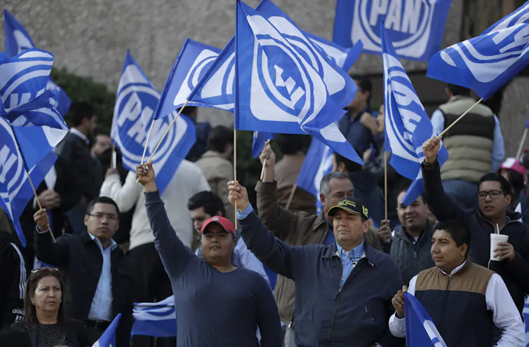 Supporters of the National Action Party (PAN) wave blue and white flags at a rally for their candidate, Ricardo Anaya, in February 2018.