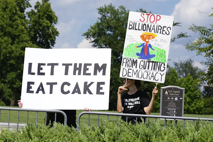 Protesters hold signs opposing President Donald Trump's tax-cut and policy bill on July 2, 2025, in Washington.