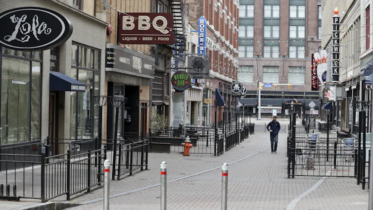 a man walks on a pedestrianized street with restaurants
