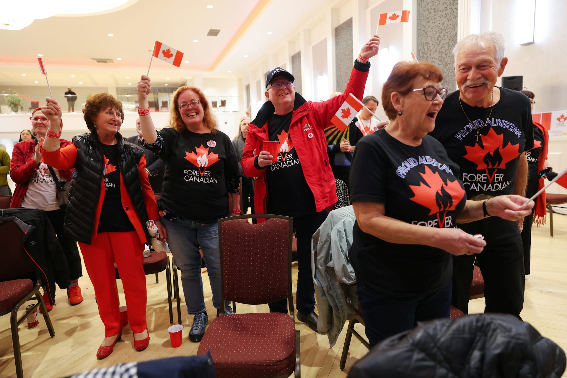Several people wearing Canada t-shirts wave small Canadian flags.
