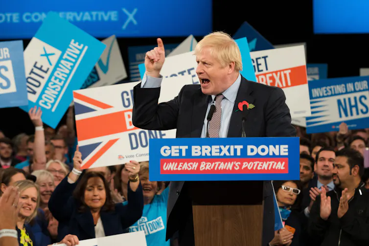 boris johnson standing at a podium bearing the slogan 'get brexit done' during the 2019 conservative election campaign.