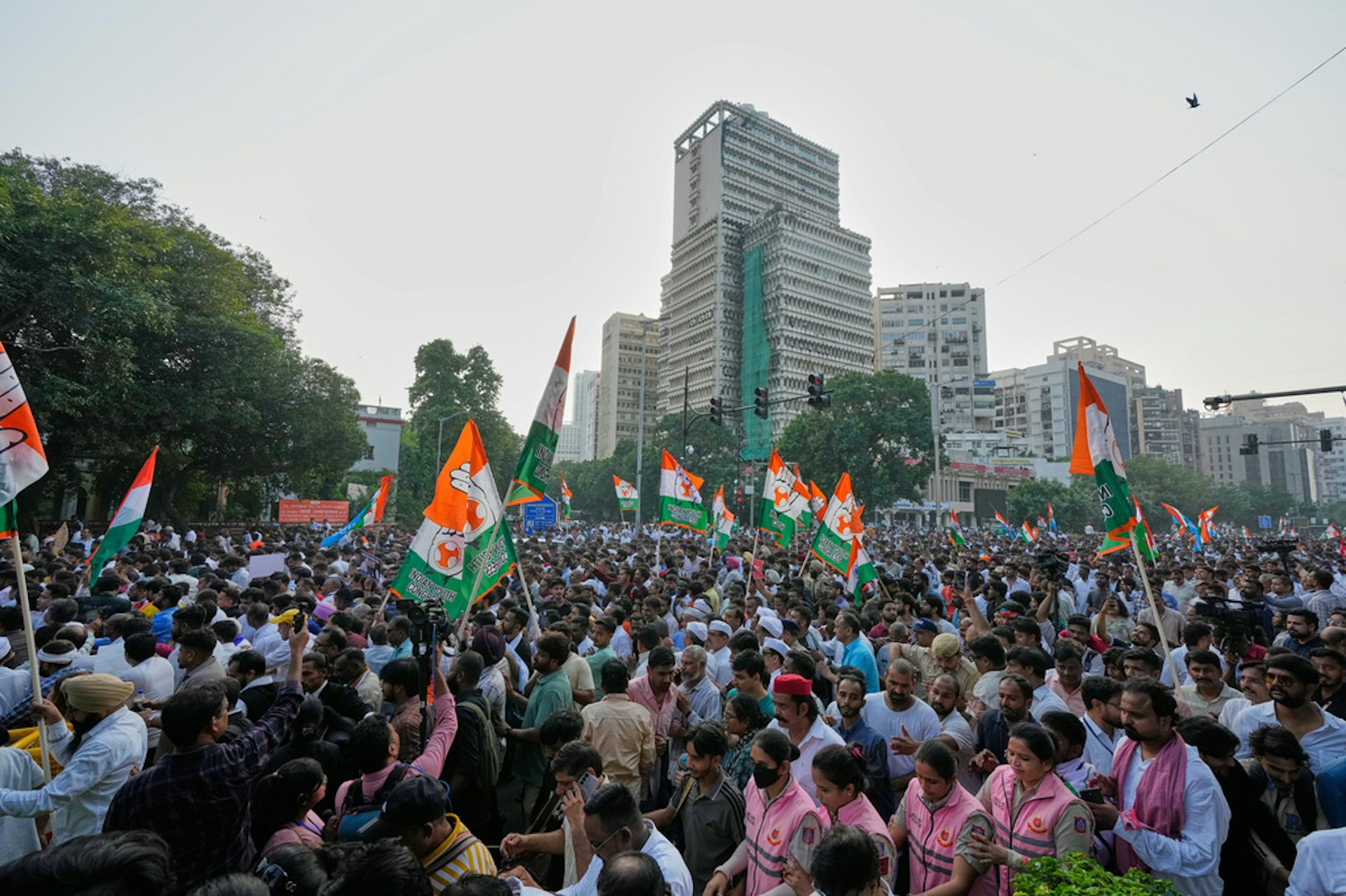 A crowd of protesters holding India's national flag walks in a procession on the streets.