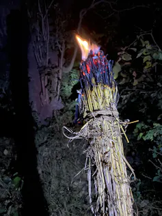 A bundle of grass with flames at the end