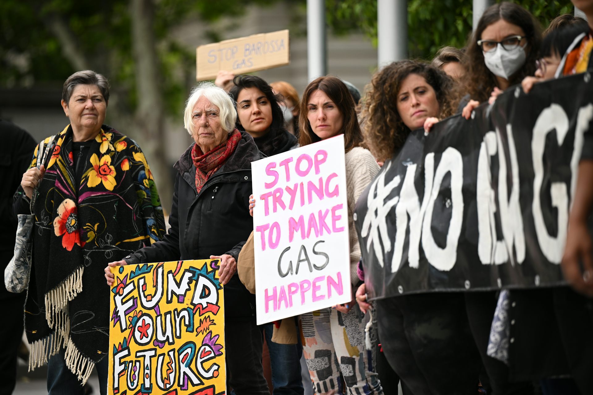A crowd of people holding signs protesting again the development of new gas projects.