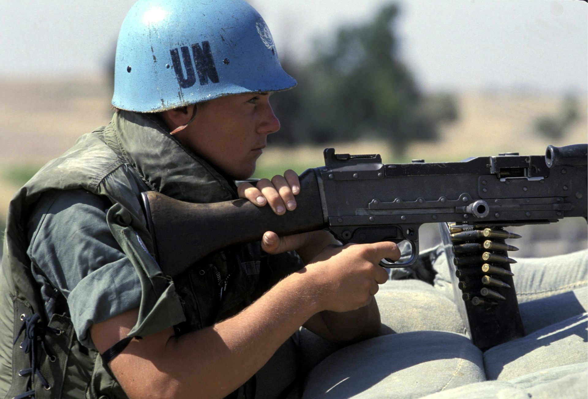 A man in a blue helmet holds a large gun
