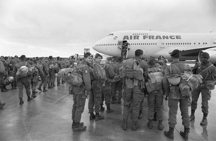 A group of soldiers stand next to a airplane with 'Air France' written on it.