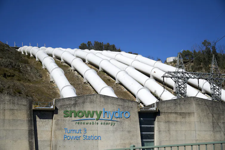 Six white pressure pipes stretch over a hillside, as part of the large renewable energy project Snowy 2.0.