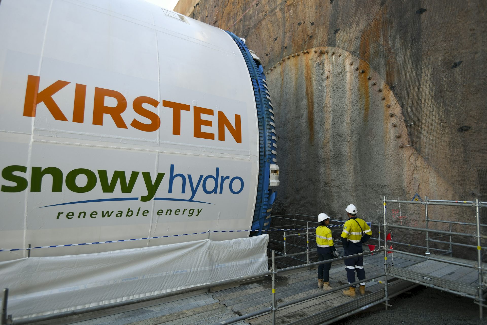 Workers look at a large machine that forms part of the large renewable energy project Snowy Hydro 2.0.