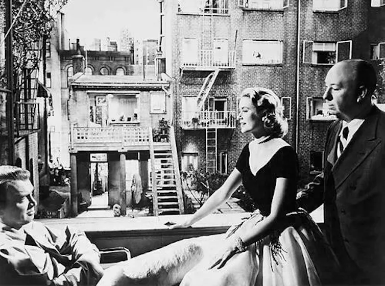 Three figures before a large open window overlooking a courtyard and apartment windows.