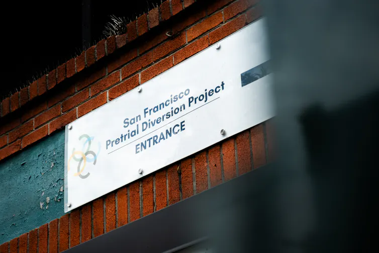 A sign on a brick wall reads 'San Francisco Pretrial Diversion Project ENTRANCE.'