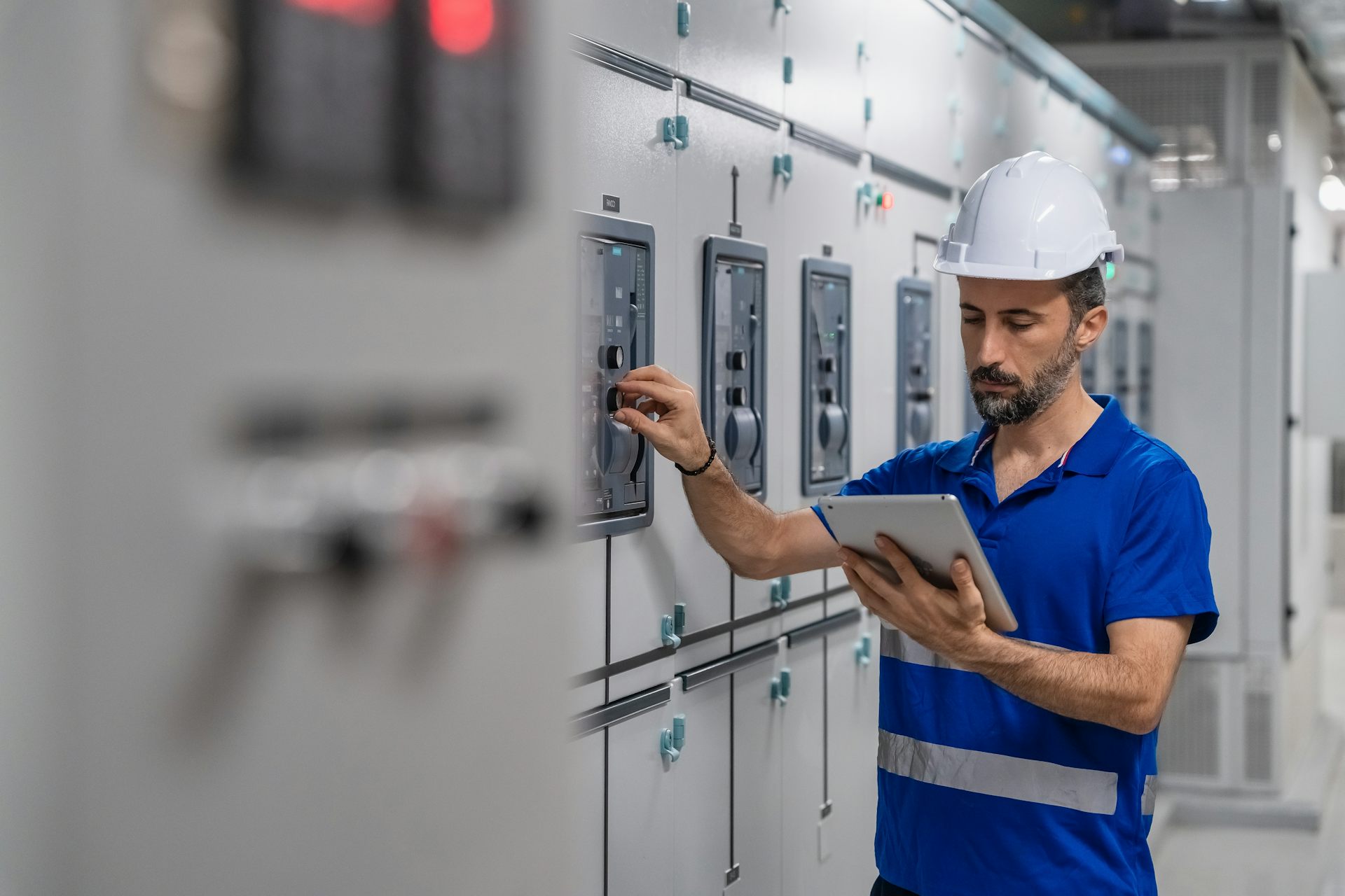 Electrical engineer adjusting power panel in control room for smart grid maintenance.