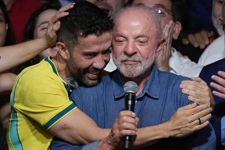 Two men embrace.