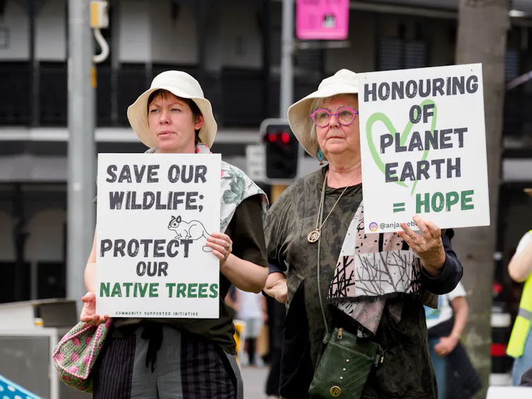 Two women hold signs advocating for environmental action.