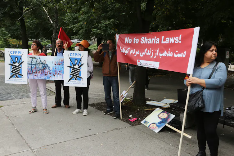 Several protesters hold a large sign saying 'No to Sharia Laws.'