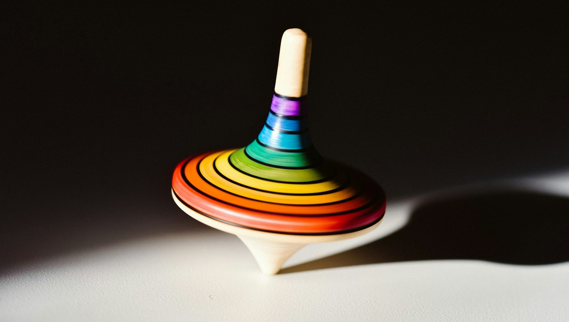 A rainbow-colored wooden top spinning.