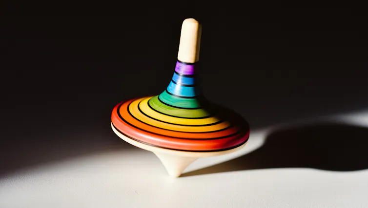 A rainbow-colored wooden top spinning.
