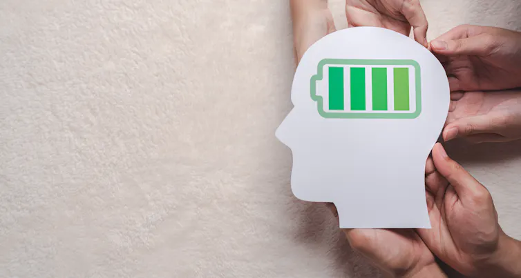 A cut-out paper silhouette of a human head, with a battery in the centre. The battery is fully charged.