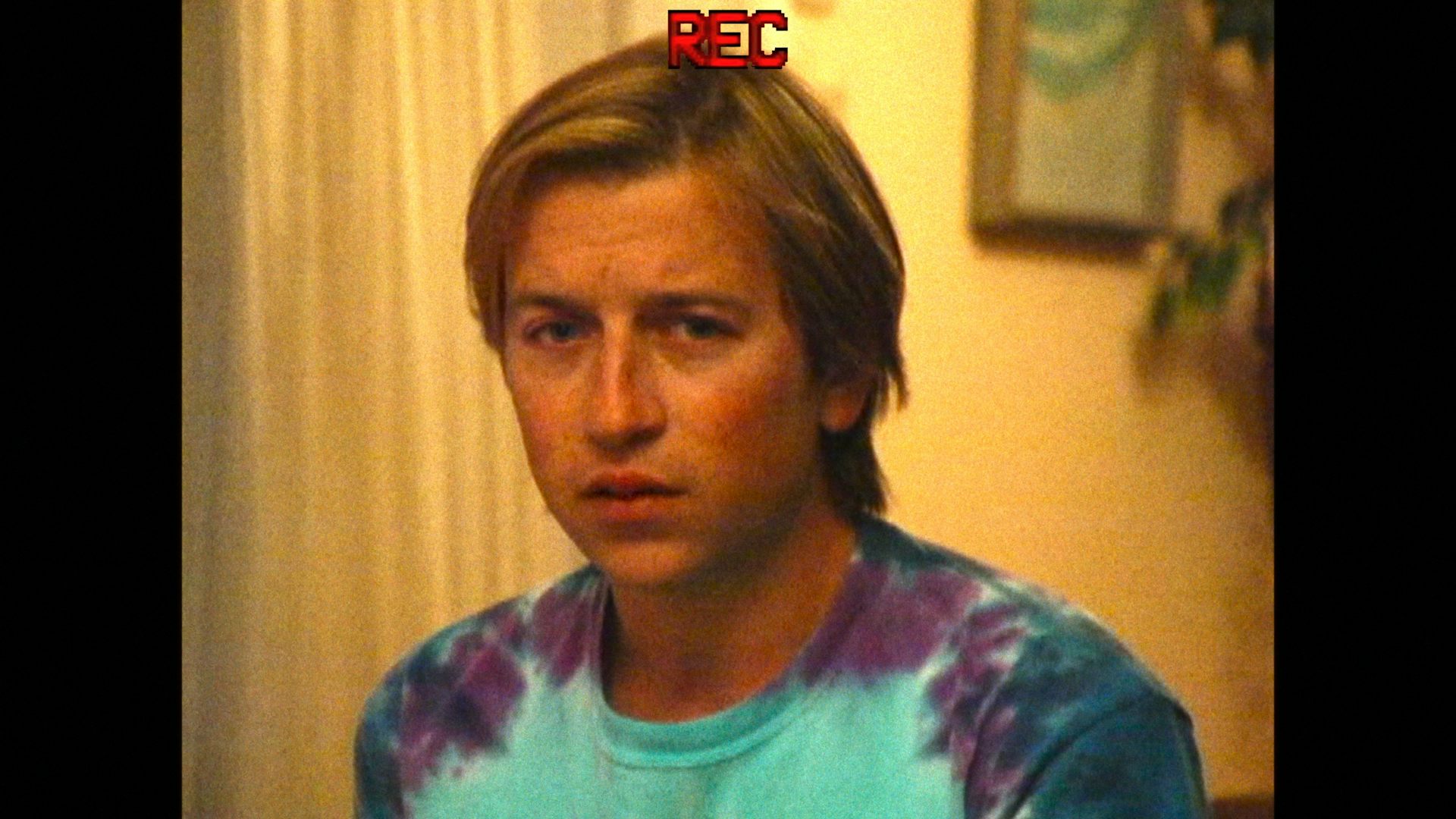A young man looking uncertain as he is recorded on video.