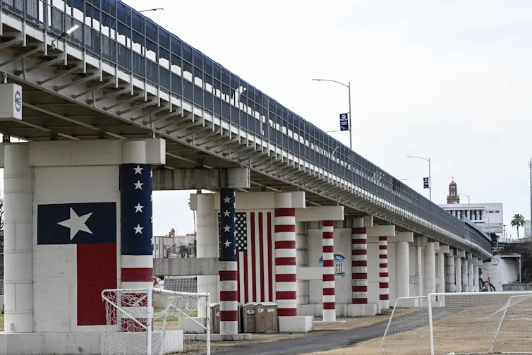 Gates at a border crossing bridge are painted with U.S. and Texas flags.