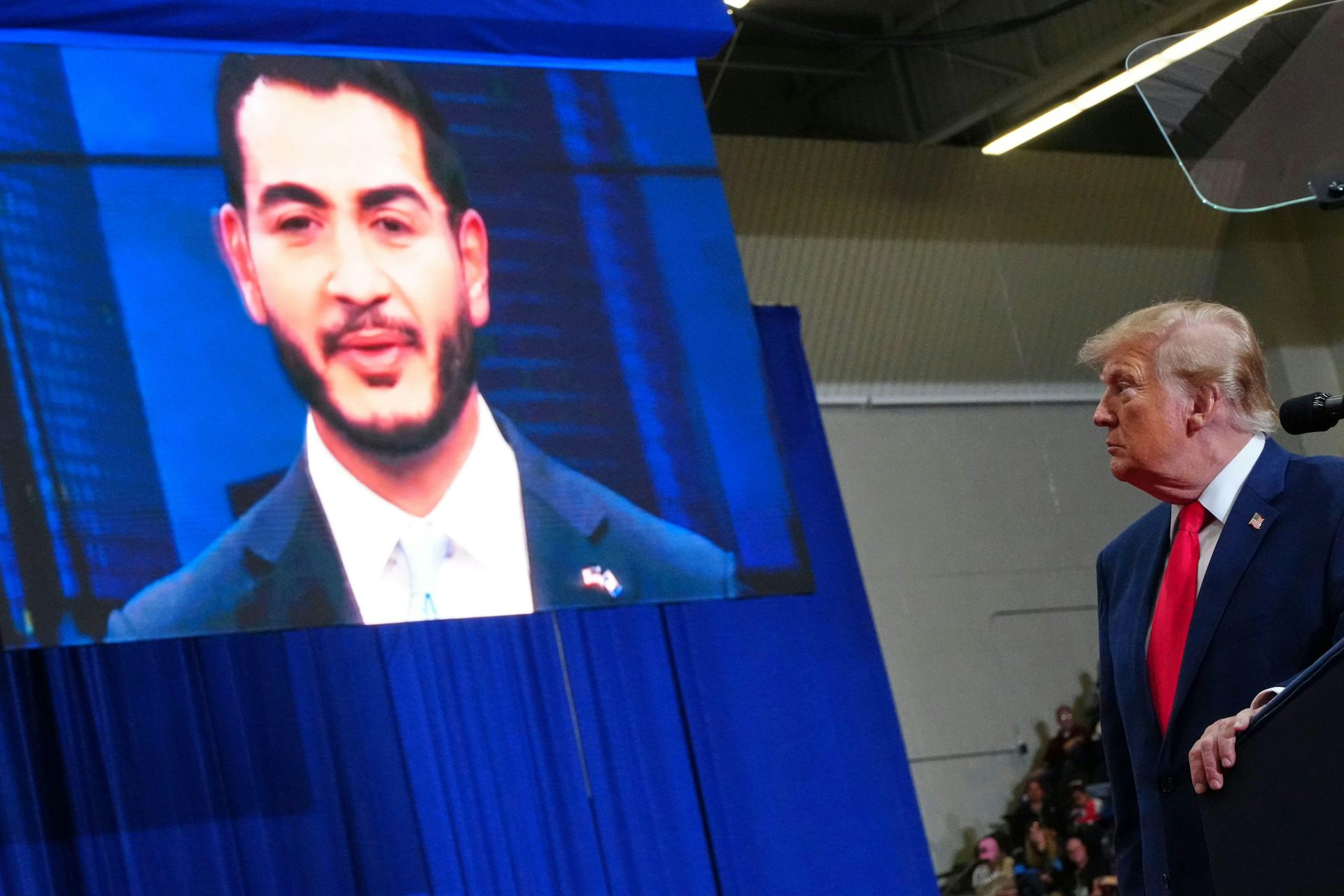 Donald Trump in stage at a rally in Michigan with am image of the Democrat candidate for the Michigan senate seat, Abdul El-Sayed