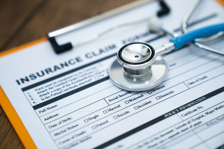 An insurance claim form on a clipboard with a stethoscope lying on it.
