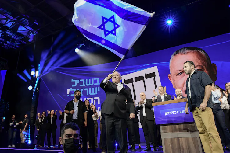 A man waves a large blue and white flag.